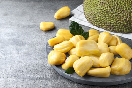 Fresh exotic jackfruit bulbs on gray table. Space for textの写真素材