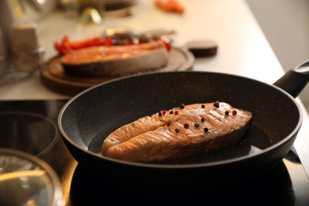 Frying pan with tasty salmon steak on cooktopの写真素材