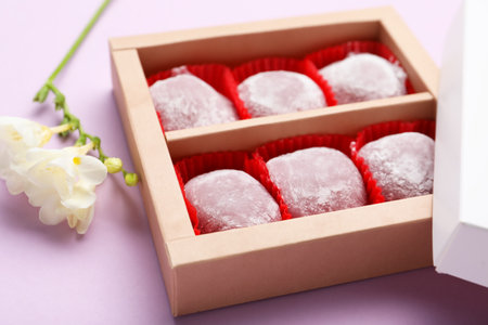 Box of delicious mochi and flowers on light background, closeup. Traditional Japanese dessertの写真素材