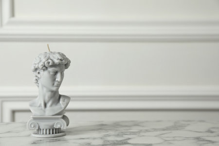 Stylish David bust candle on white marble table. Space for textの写真素材