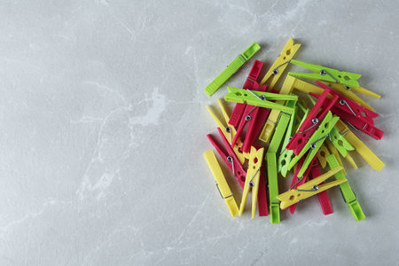 Colorful plastic clothespins on gray table, flat lay. Space for text