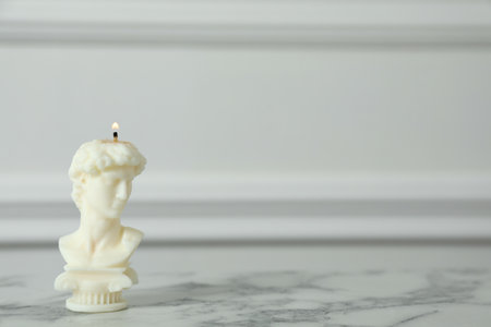 Stylish David bust candle on white marble table. Space for textの写真素材