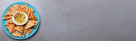 Delicious pita chips with hummus on gray table, top view. Space for textの写真素材