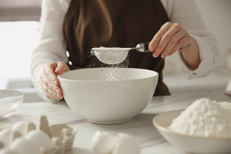 Woman making dough at table in kitchen, closeupの写真素材