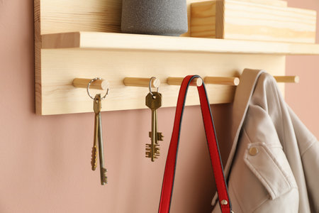 Wooden rack with hanging keys, jacket and purse on beige wall indoorsの写真素材
