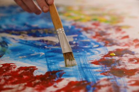 Man painting on canvas with brush, closeup. young artist
