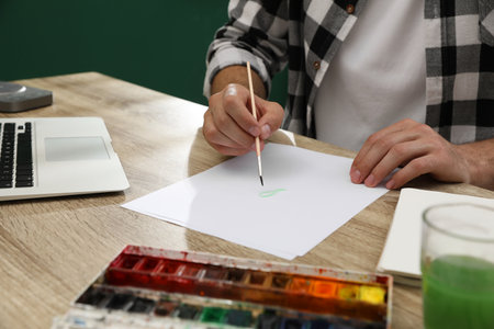 Man drawing with paints at table, closeup. distance learning