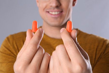 Man with foam ear plugs on gray background, closeupの写真素材