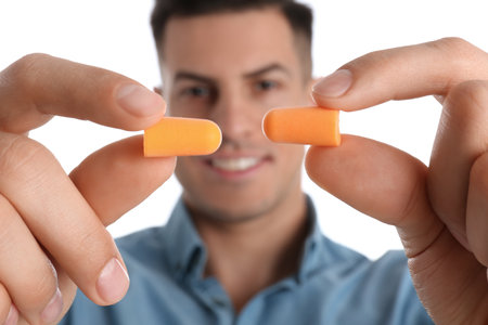 Man with foam ear plugs against white background, focus on handsの写真素材