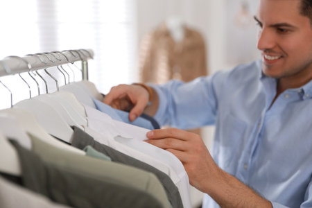 Man choosing clothes near rack in modern boutiqueの写真素材