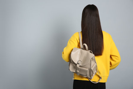 Young woman with stylish leather backpack on grey background, back view. Space for textの写真素材