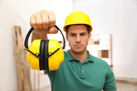 Worker holding safety headphones indoors, focus on device. Hearing protectionの写真素材