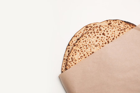 Tasty matzos wrapped with paper on white background, top view. Passover (Pesach) celebrationの写真素材
