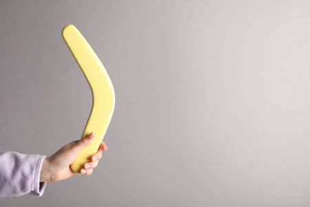 Woman holding boomerang on gray background, closeup. Space for textの写真素材