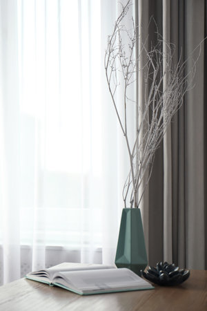 Beautiful tree twigs in vase on wooden table indoorsの写真素材