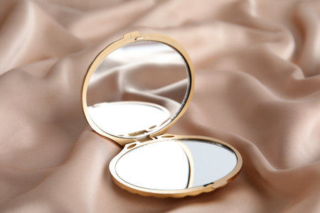 Bright cosmetic pocket mirror on rose gold fabricの写真素材