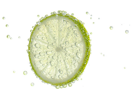 Fresh lime slice in sparkling water on white backgroundの写真素材