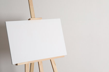 Wooden easel with blank canvas on light background. Space for textの写真素材
