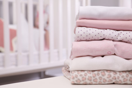 Stack of clean girl's clothes on table indoors. Space for textの写真素材