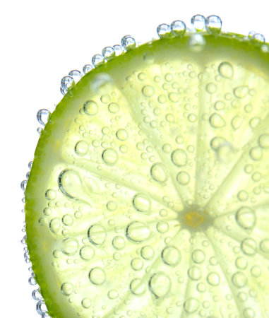 Fresh lime slice in sparkling water on white background, closeupの写真素材