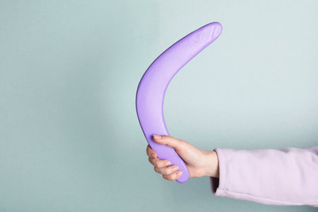 Woman holding boomerang on light gray background, closeup. Space for textの写真素材