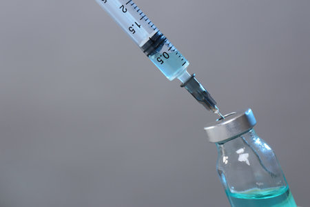 Filling syringe with medicine from vial on gray background, closeup. Space for textの写真素材