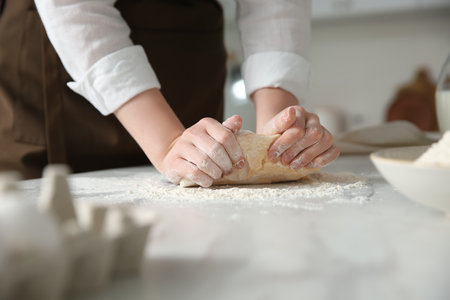 Woman kneading dough at table in kitchen, closeupの写真素材