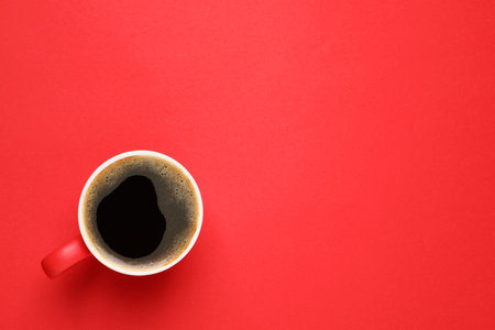 Cup of aromatic coffee on red background, top view. Space for textの写真素材