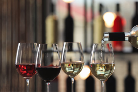 Pouring white wine from bottle into glass indoors, closeupの写真素材