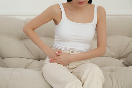 Woman suffering from appendicitis inflammation on sofa indoors, closeupの写真素材
