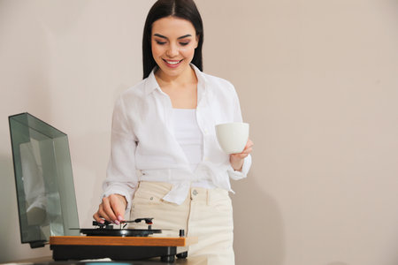 Woman using turntable on beige background. Space for textの写真素材