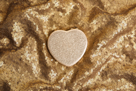 Stylish heart shaped cosmetic pocket mirror on gold fabric, top viewの写真素材