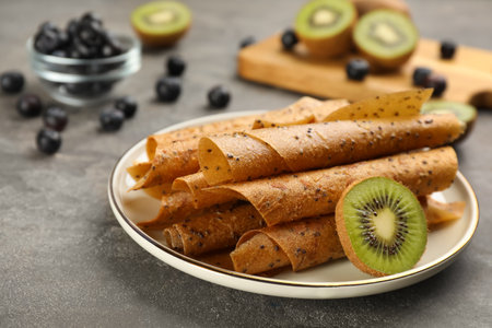 Delicious fruit leather rolls and kiwi slice on gray tableの写真素材