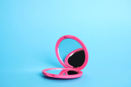 Stylish cosmetic pocket mirror on light blue backgroundの写真素材