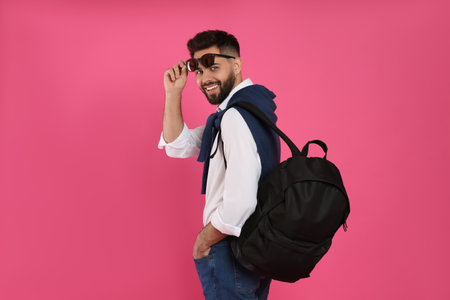 Young man with stylish backpack on pink backgroundの写真素材