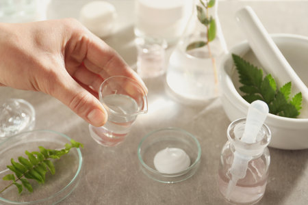 Scientist making cosmetic product at gray table, closeupの写真素材