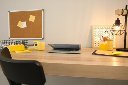 Stylish workplace with laptop on wooden desk near light wall. interior designの写真素材