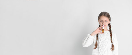 Sick little girl using nasal spray on white backgroundの写真素材