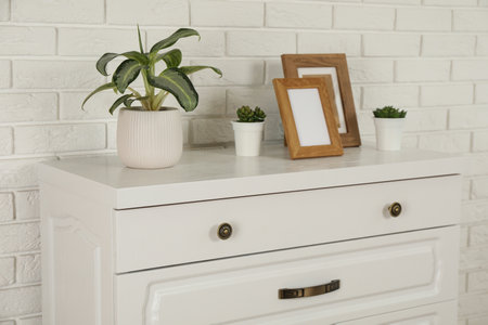 Modern chest of drawers with decor near white brick wallの写真素材