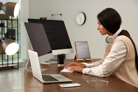 Programmer with headphones working at desk in office