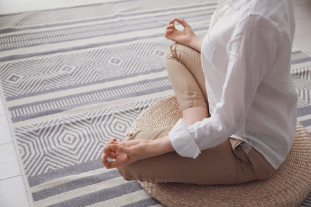 Woman meditating on wicker mat at home, closeup. Space for textの写真素材