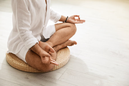 Young man meditating on straw cushion at home, closeup. Space for textの写真素材