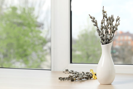 Beautiful pussy willow branches on window sill indoors, space for textの写真素材