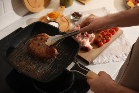 Man taking cooked tasty meat from frying pan, closeupの写真素材
