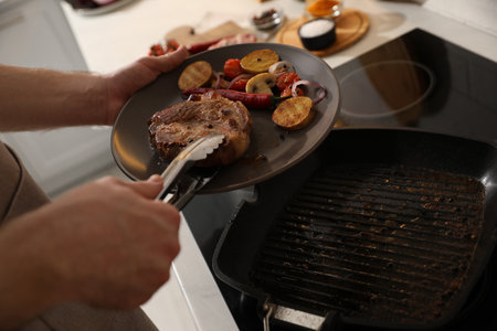 Man with tasty meat and vegetables cooked on frying pan, closeupの写真素材