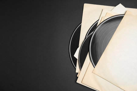 Vintage vinyl records in paper sleeves on black background, flat lay. Space for textの写真素材