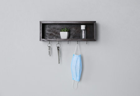 Wooden hanger for keys with different stuff on light gray wallの写真素材