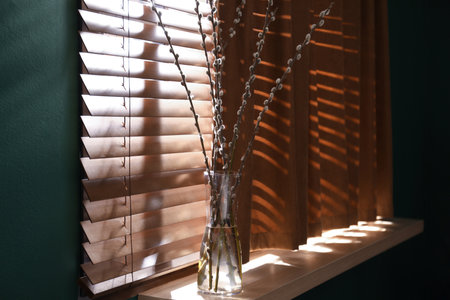 Glass vase with pussy willow tree branches on wooden windowsillの写真素材