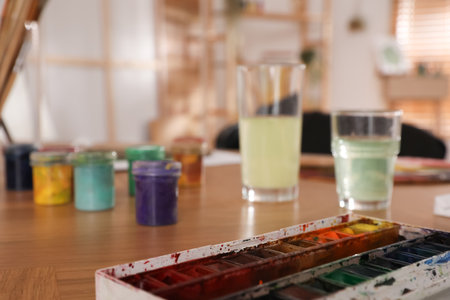Paints on wooden table in art studio, closeup. Space for textの写真素材