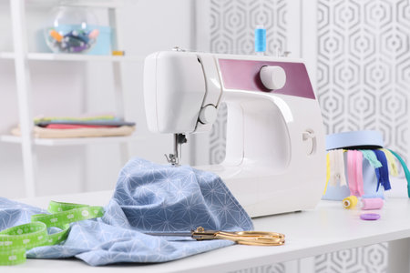 Modern sewing machine, fabric and accessories on table indoorsの写真素材